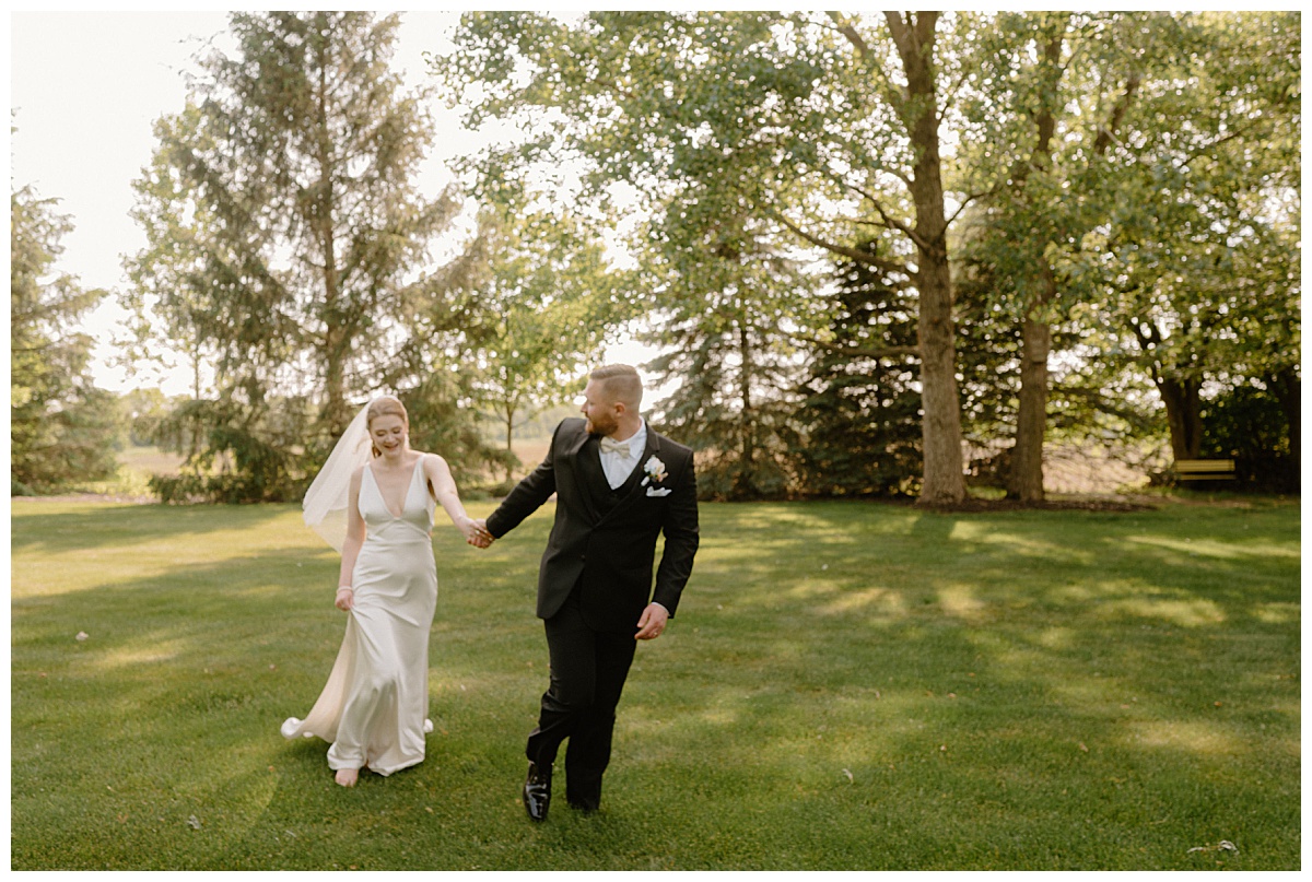 newlyweds run in grassy lawn at backyard summer celebration