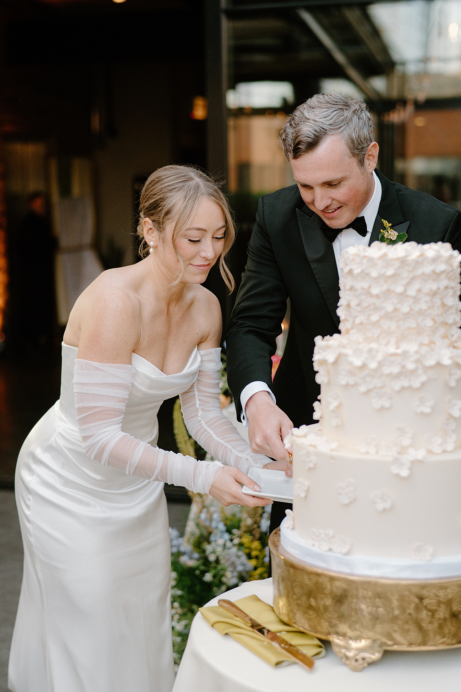 newlyweds cut three tier cake at reception by Chicago wedding photographer