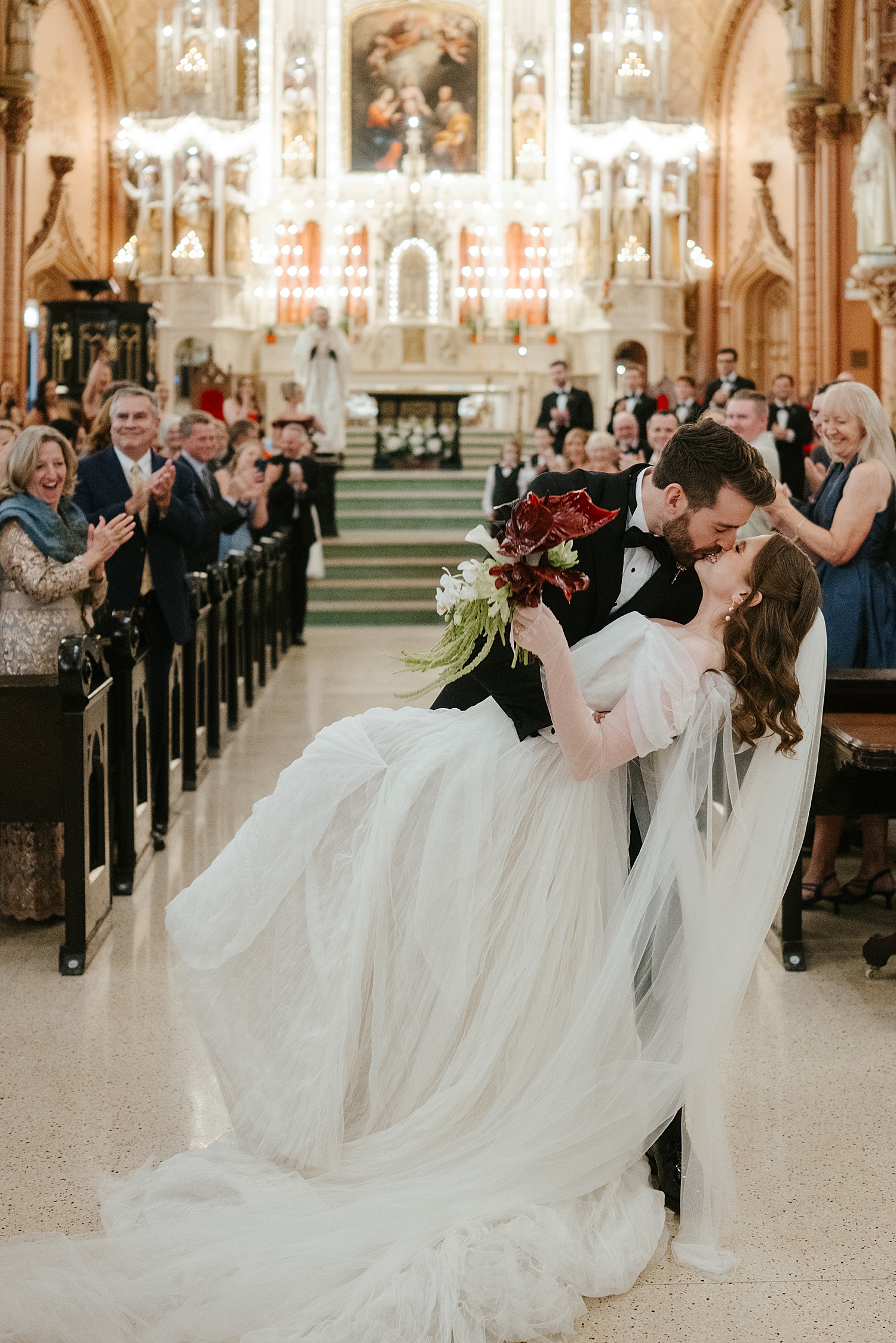 newlyweds dip for a kiss at end of aisle before heading to their reception at Skyline Loft