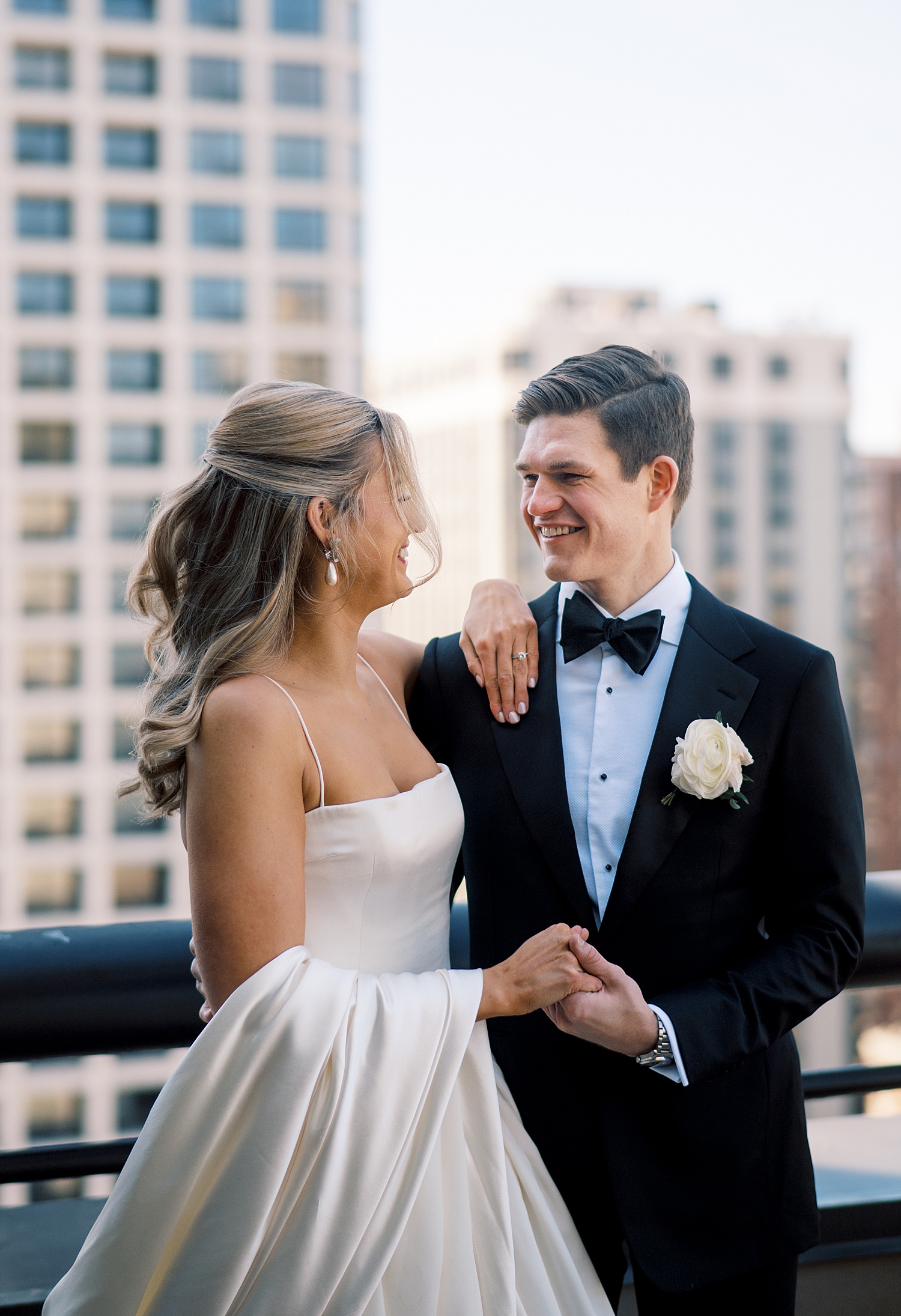 bride and groom hold hands on balcony by Chicago wedding photographer
