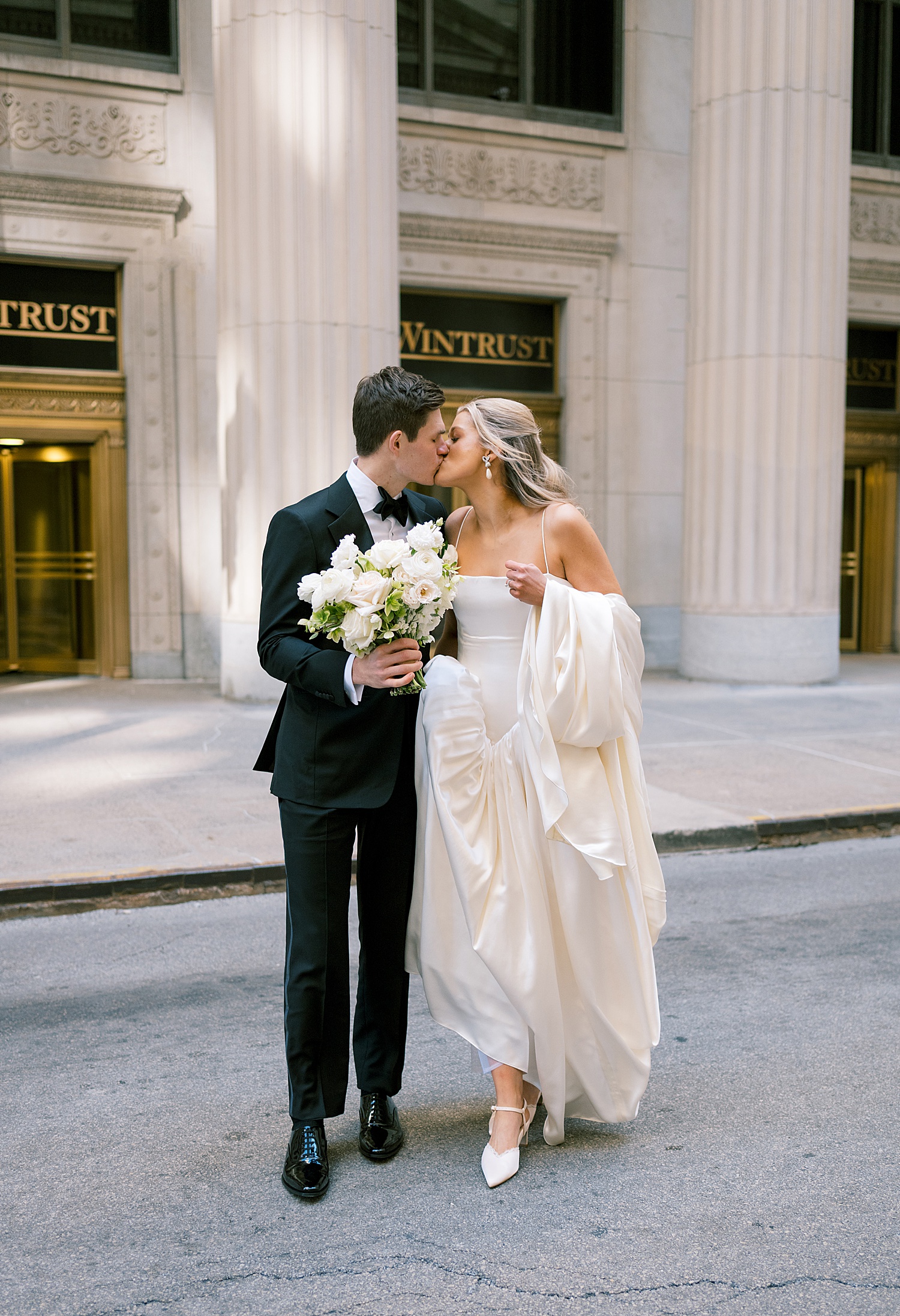 wedding couple share a kiss on street by Morgan McIntire Photography
