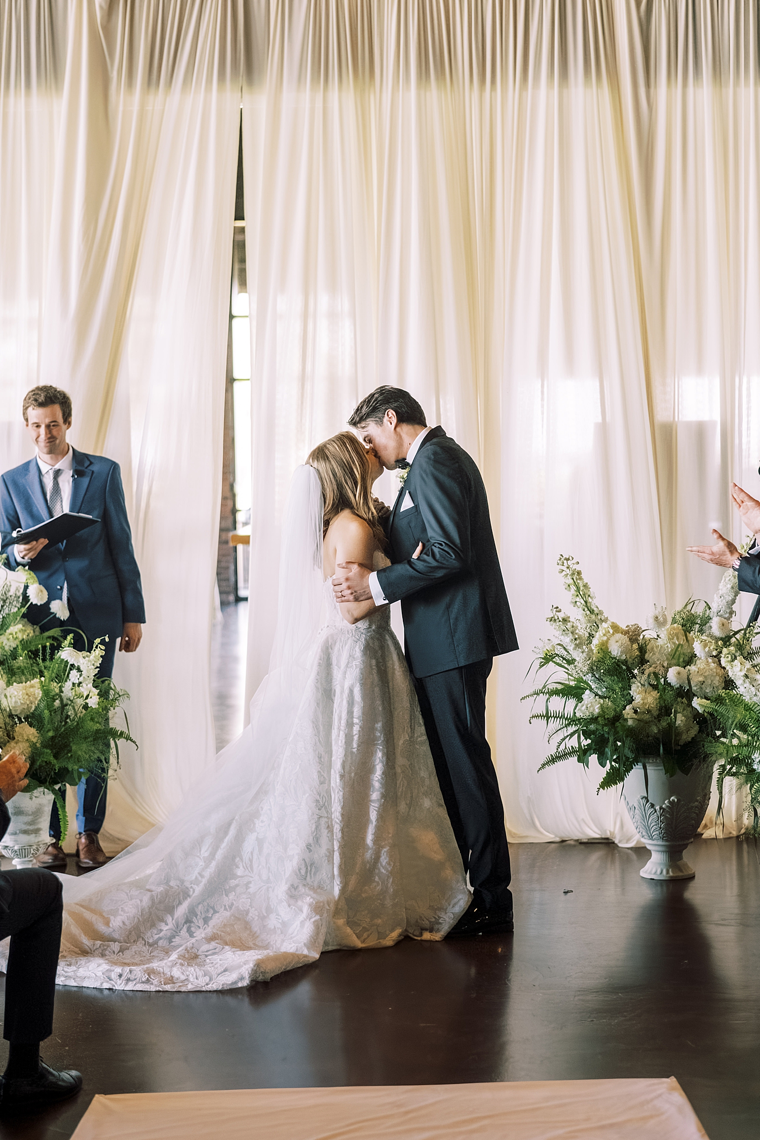 newlyweds kiss at the alter in front of drapes by Morgan McIntire Photography