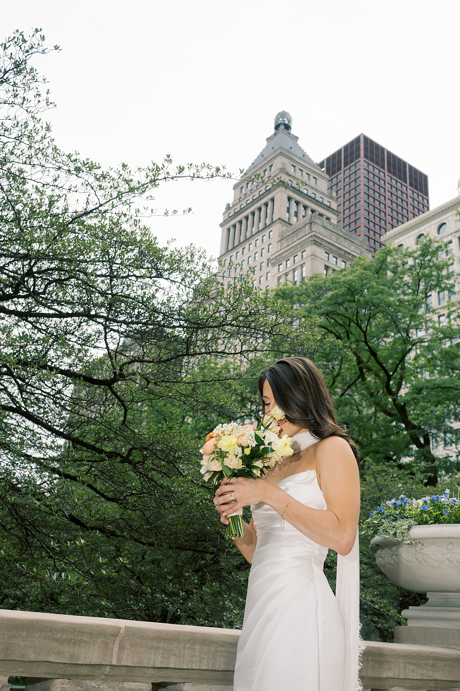 bride sniffs her bouquet on downtown sidewalk for Italian Inspired day