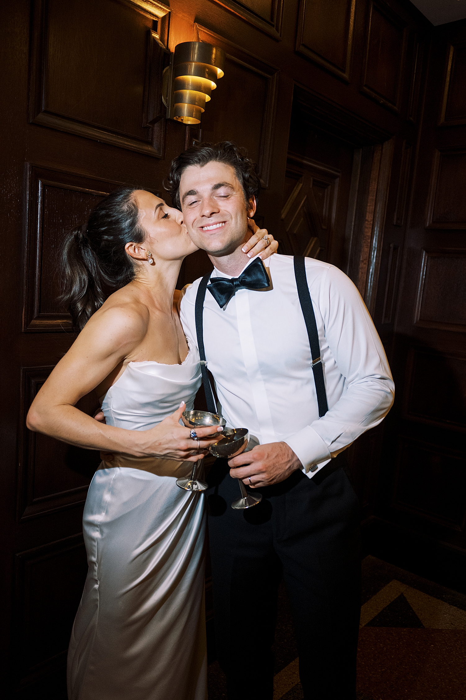 brunette bride reaches up to kiss groom on cheek by Morgan McIntire Photography